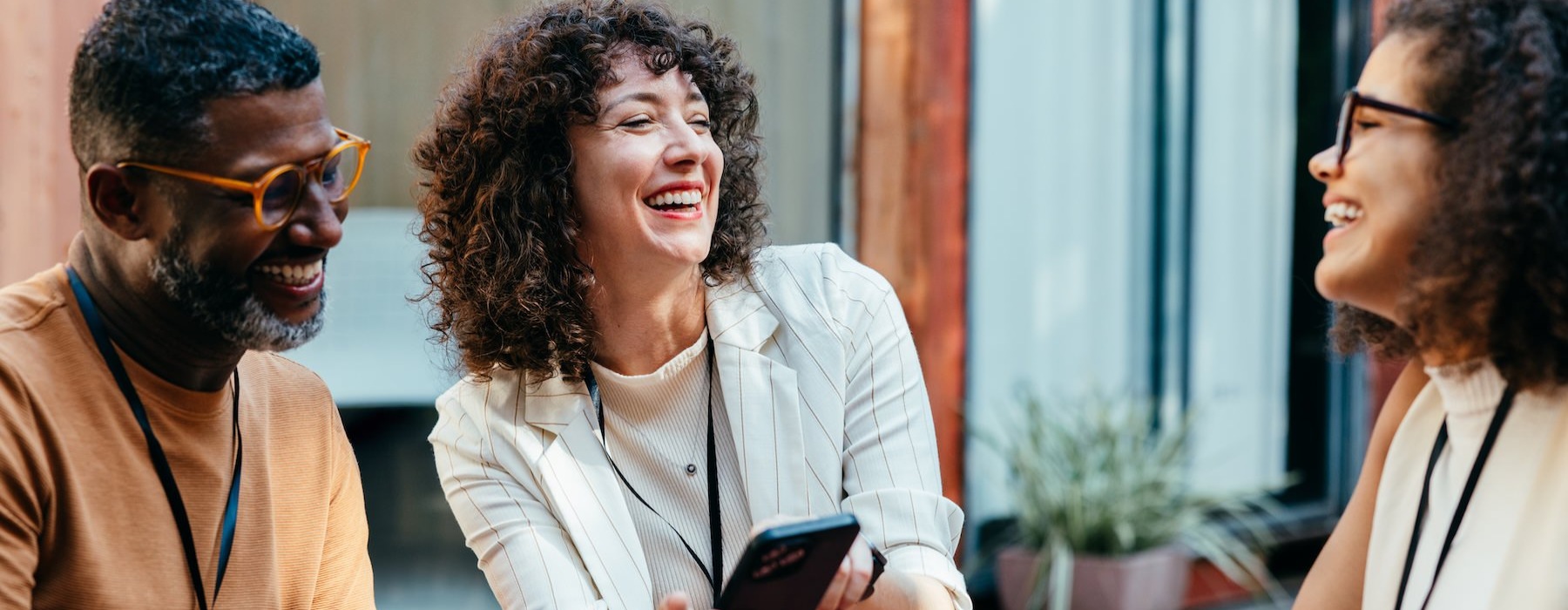three people laughing and holding a phone