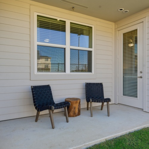 two chairs on a patio with a yard