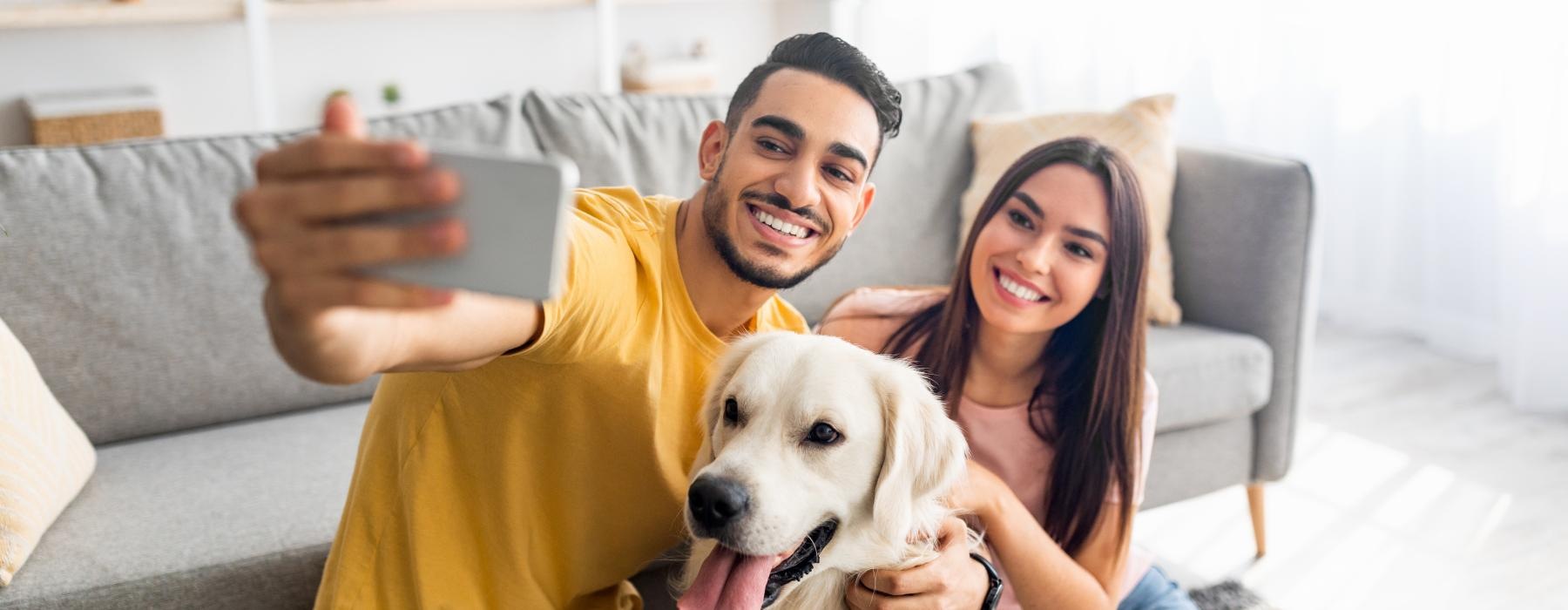 a man and woman sitting on a couch with a dog